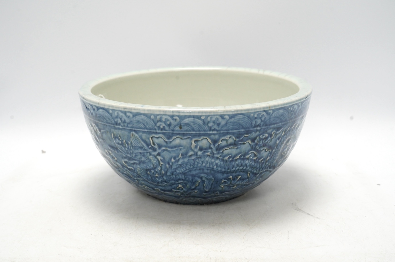 A large Chinese blue and white ‘dragon’ bowl decorated in low relief, 28cm in diameter. Condition - good